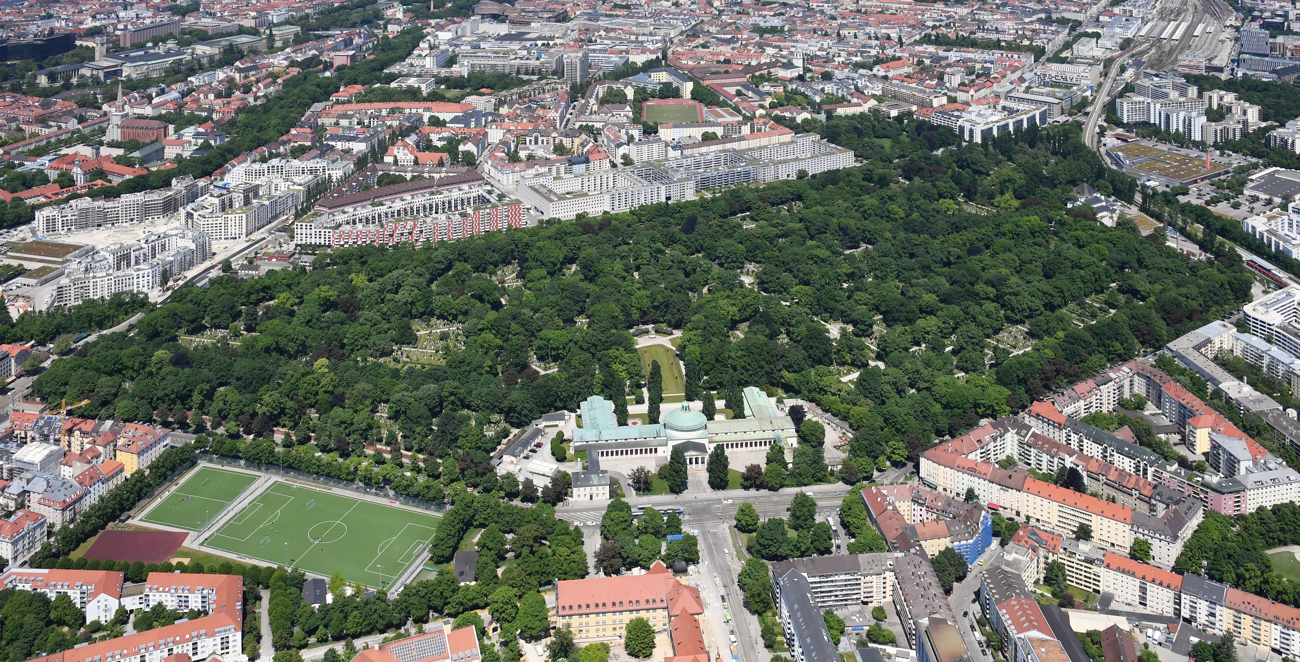 Luftaufnahme des baumbestandenen Ostfriedhofs München mit der Aussegnungshalle im Vordergrund